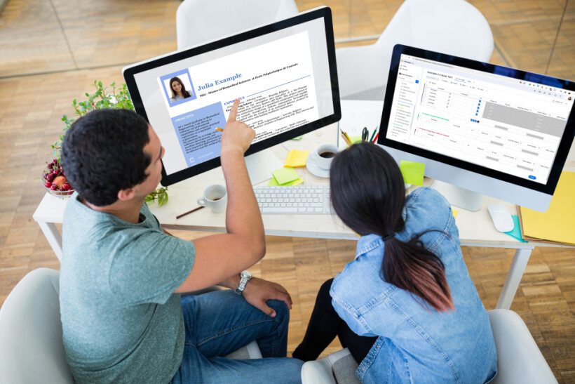 Two people reviewing a candidate’s resume on a desktop screen during a recruitment process.