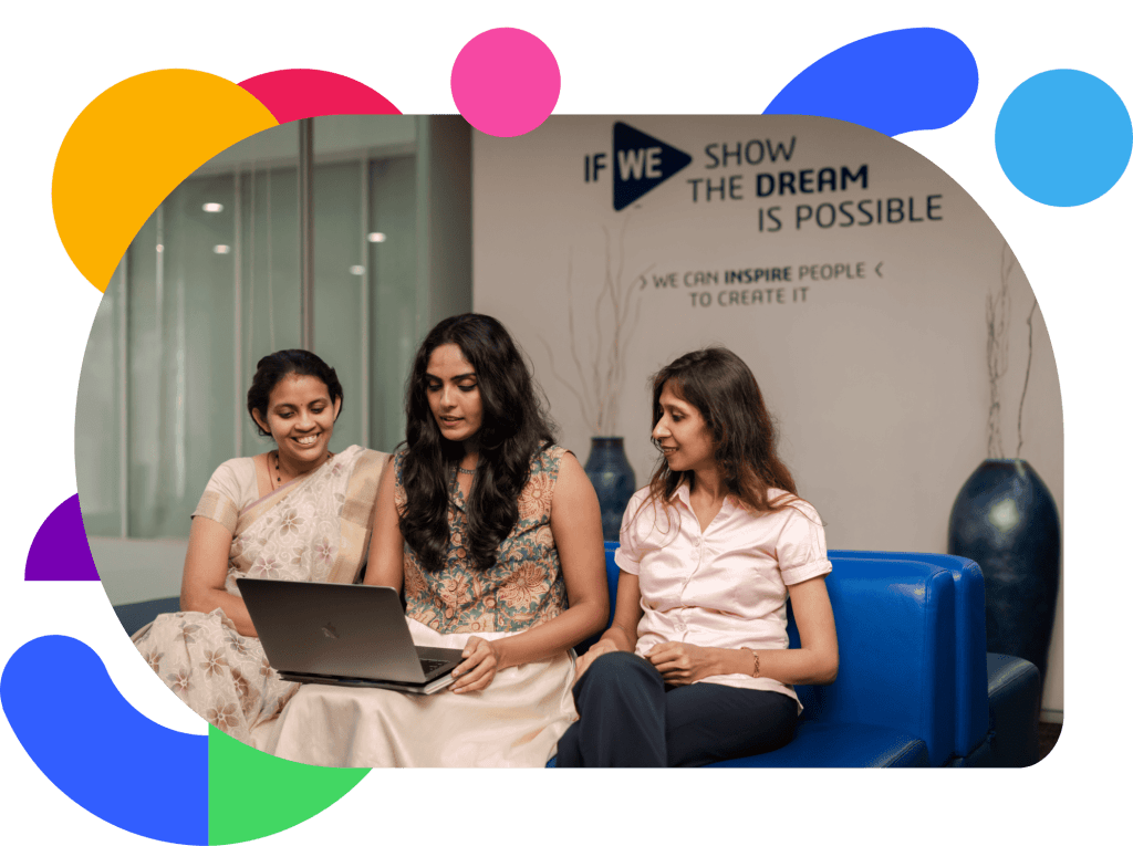 Three colleagues sitting together on a couch reviewing work on a laptop in a modern office space at Dassault Systèmes.